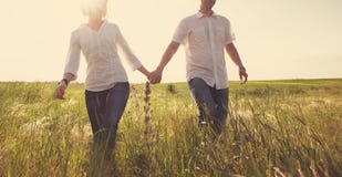 Happy couple holding hands walking through a meadow Royalty Free Stock Photo