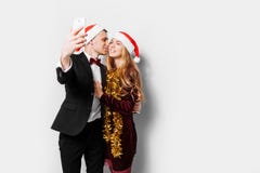 Happy couple of lovers in Santa Claus hats, the guy kisses the g royalty free stock photography Happy couple of lovers in Santa Claus hats, the guy kisses the g royalty free stock photography
