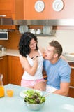 Happy Couple Playfully Eating Salad At Kitchen Stock Images