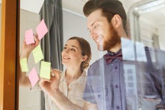 Happy creative team writing on stickers at office Stock Image Happy creative team writing on stickers at office Stock Image