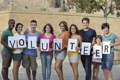 Happy and diverse volunteer group. Holding sign Happy and diverse volunteer group. Holding sign