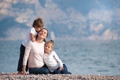 Happy dreaming beautiful family consisting mother and two kids outdoors near sea stock photos Happy dreaming beautiful family consisting mother and two kids outdoors near sea stock photos