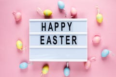 Happy Easter text on lightbox on pink pastel paper background with yellow, pink, blue eggs and bunnies. Bright template for Easter royalty free stock photos Happy Easter text on lightbox on pink pastel paper background with yellow, pink, blue eggs and bunnies. Bright template for Easter royalty free stock photos