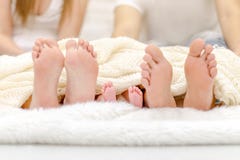 Happy familiy in bed. Mother father and baby feet under blanket. Tree pairs of legs. Stock Photography Happy familiy in bed. Mother father and baby feet under blanket. Tree pairs of legs. Stock Photography