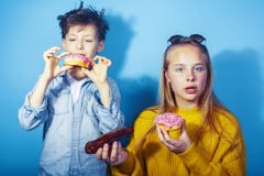 Happy family brother and sister eating donuts on blue background, lifestyle people concept, boy and girl eating stock photo Happy family brother and sister eating donuts on blue background, lifestyle people concept, boy and girl eating stock photo
