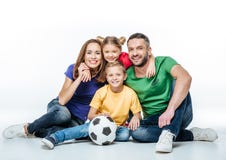 Happy family in colored t-shirts sitting together with soccer ball stock photos Happy family in colored t-shirts sitting together with soccer ball stock photos