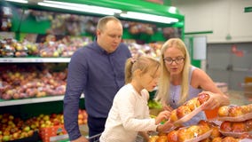 Happy family doing shopping. Family of four passing fruit section in the mall. Family makes purchases in the supermarket stock video Happy family doing shopping. Family of four passing fruit section in the mall. Family makes purchases in the supermarket stock video