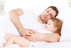 Happy family father and child baby daughter sleeping in bed stock image Happy family father and child baby daughter sleeping in bed stock image