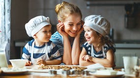 Happy family in kitchen. mother and children preparing dough, ba