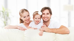 Happy family mother, father, child baby daughter at home on sofa playing and laughing