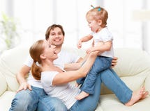 Happy family mother, father, child baby daughter at home on sofa playing and laughing