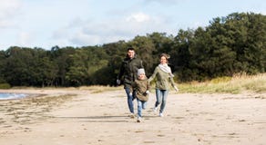 Happy family running along autumn beach stock photos Happy family running along autumn beach stock photos