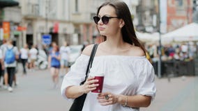 Happy female tourist with a cup of coffee stands on crowded city street walks and waits for a guy on a date, people and stock video footage Happy female tourist with a cup of coffee stands on crowded city street walks and waits for a guy on a date, people and stock video footage