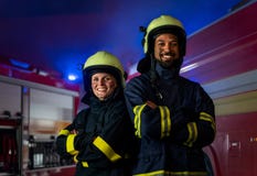 Happy firefighters man and woman after action looking at camera with fire truck in background