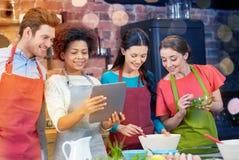 Happy friends with tablet pc cooking in kitchen Stock Photography Happy friends with tablet pc cooking in kitchen Stock Photography