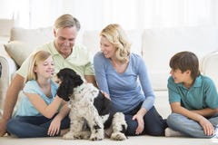 Happy Girl Playing With Dog While Family Looking At Her royalty free stock image Happy Girl Playing With Dog While Family Looking At Her royalty free stock image