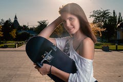 Happy girl with skateboard in summer city backlit stock image Happy girl with skateboard in summer city backlit stock image