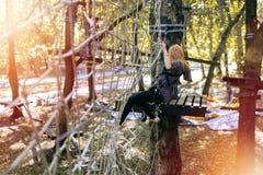 Happy girl, woman, climbing gear in an adventure, rope road, insurance, attraction, amusement park, active recreation, autumn stock photography Happy girl, woman, climbing gear in an adventure, rope road, insurance, attraction, amusement park, active recreation, autumn stock photography