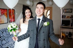 Happy groom with balloons in his hands, indoors at wedding day, the bride in the background. royalty free stock photos Happy groom with balloons in his hands, indoors at wedding day, the bride in the background. royalty free stock photos