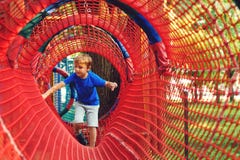 Happy Kid Overcomes Obstacles In Rope Adventure Park. Summer Holidays Concept. Little Boy Playing At Rope Adventure Park. Modern Royalty Free Stock Images