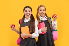 Happy kids in school uniforms hold books and apples for healthy eating school meal, snack