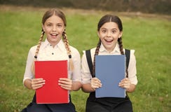 Happy kids in school uniforms show colorful schoolbooks covers outdoors, books