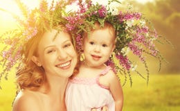 Happy laughing daughter hugging mother in wreaths of summer flow