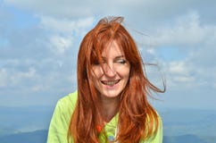 Happy laughing woman with red hear tourist in the sunlight in the mountains in sky background, wind ruffles her hair royalty free stock photography Happy laughing woman with red hear tourist in the sunlight in the mountains in sky background, wind ruffles her hair royalty free stock photography