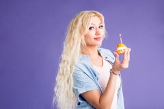 Happy lovely curly young woman holding birthday cupcake with candle royalty free stock photography Happy lovely curly young woman holding birthday cupcake with candle royalty free stock photography