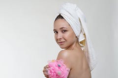 Pretty young girl with beautiful fresh skin, healthy look and wonderful smile in a towel posing with a sponge on white background stock photography Pretty young girl with beautiful fresh skin, healthy look and wonderful smile in a towel posing with a sponge on white background stock photography