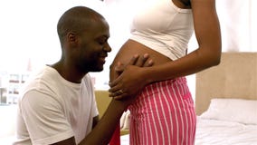 Happy man kissing belly of pregnant woman