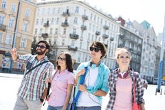 Happy man showing something to male and female friends on city street stock photo Happy man showing something to male and female friends on city street stock photo