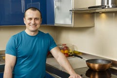 Happy man standing in his kitchen. Leaning on the stove Royalty Free Stock Image Happy man standing in his kitchen. Leaning on the stove Royalty Free Stock Image