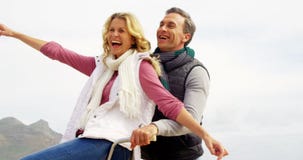Happy mature couple sitting on bicycle with arms outstretched