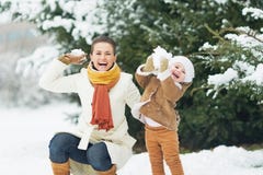 Happy mother and baby throwing snowballs in winter park stock photos Happy mother and baby throwing snowballs in winter park stock photos