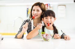 Mother and child in kitchen eating salad Royalty Free Stock Image Mother and child in kitchen eating salad Royalty Free Stock Image