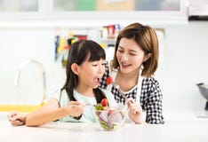 Mother and child in kitchen eating salad Stock Image Mother and child in kitchen eating salad Stock Image