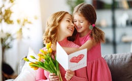 Happy mother`s day! child daughter gives mother a bouquet of flowers to tulips and postcard