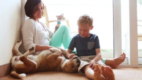 Happy mother and son family on the home floor with friendly beagle dog