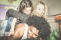 Happy multiracial mom and dad playing with mixed race daughter stock image Happy multiracial mom and dad playing with mixed race daughter stock image