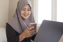 Happy Muslim Woman Working with Laptop and Smart Phone in Her Bedroom stock images Happy Muslim Woman Working with Laptop and Smart Phone in Her Bedroom stock images