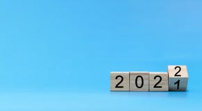 Happy New Year 2022 celebration. number written on wooden cube block stack on blue background