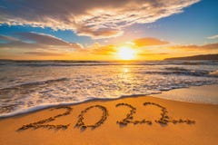 Happy New Year 2022 concept, lettering on the beach. Written text on the sea beach at sunrise