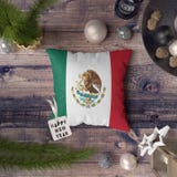 Happy New Year tag with Mexico flag on pillow. Christmas decoration concept on wooden table with lovely objects royalty free stock photography Happy New Year tag with Mexico flag on pillow. Christmas decoration concept on wooden table with lovely objects royalty free stock photography