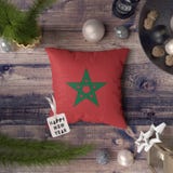 Happy New Year tag with Morocco flag on pillow. Christmas decoration concept on wooden table with lovely objects stock images Happy New Year tag with Morocco flag on pillow. Christmas decoration concept on wooden table with lovely objects stock images