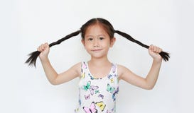 Happy Of Little Asian Child Girl Holding Pigtail On White Background. Portrait Smiling Kid With Two Pigtails Stock Photo