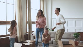 Happy parents and children dancing celebrating moving day, slow motion