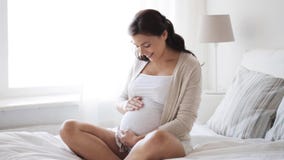 Happy pregnant woman touching her tummy at home 12