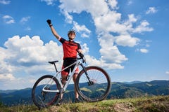 Happy professional sportsman cyclist standing with cross country bicycle on a hill, rasing hand royalty free stock photos Happy professional sportsman cyclist standing with cross country bicycle on a hill, rasing hand royalty free stock photos