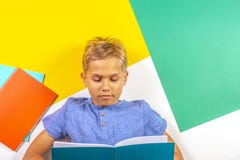 Happy pupil boy reading book notebook. Top view, colorful background Royalty Free Stock Photo Happy pupil boy reading book notebook. Top view, colorful background Royalty Free Stock Photo